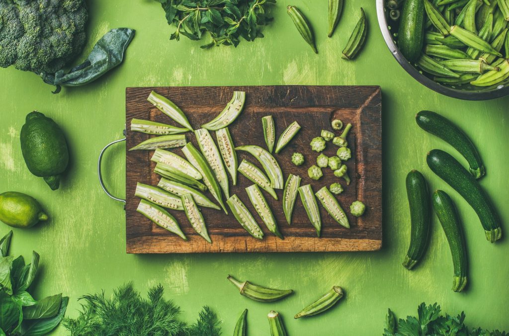 Flay-lay of green vegetables and greens on wooden board